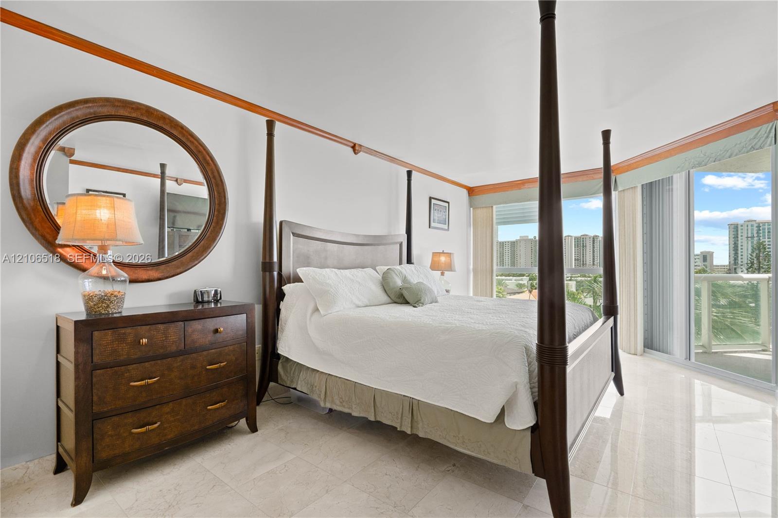 Spacious room featuring light-toned stone flooring, custom natural wood crown molding, and floor-to-ceiling glass sliding doors opening to an outdoor terrace