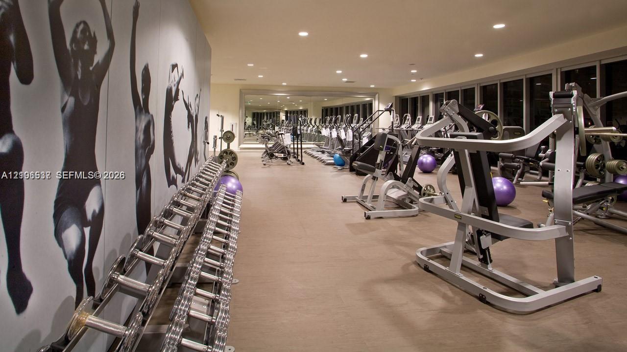 Fitness center featuring wall-to-wall mirrors, recessed lighting, and extensive floor-to-ceiling glass windows