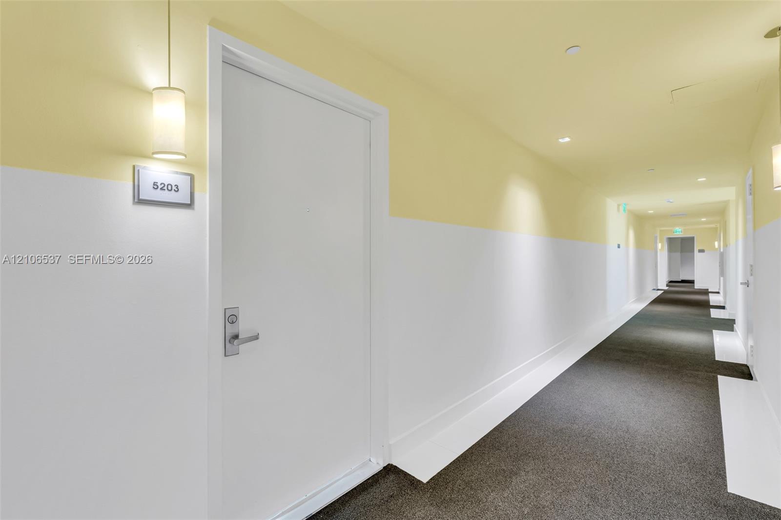 Hallway featuring two-tone wall paint, recessed lighting, carpeted flooring, and wall-mounted cylindrical sconces