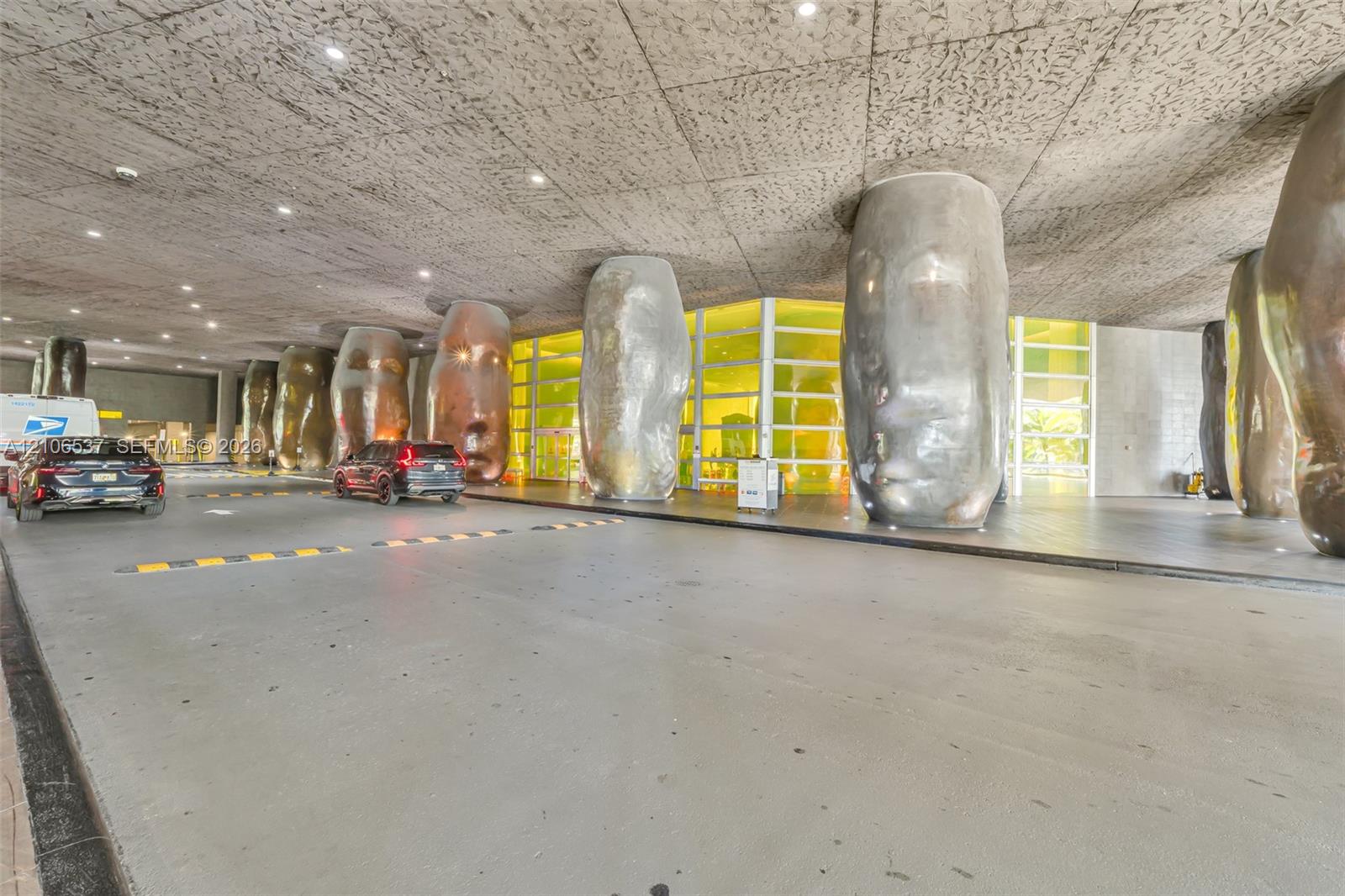 Covered porte-cochre featuring a textured concrete ceiling, recessed lighting, and sculptural metallic columns