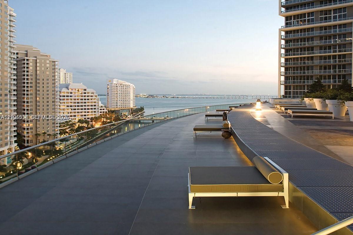 Expansive outdoor terrace featuring large-format tile flooring, a glass panel railing, and integrated linear ground lighting