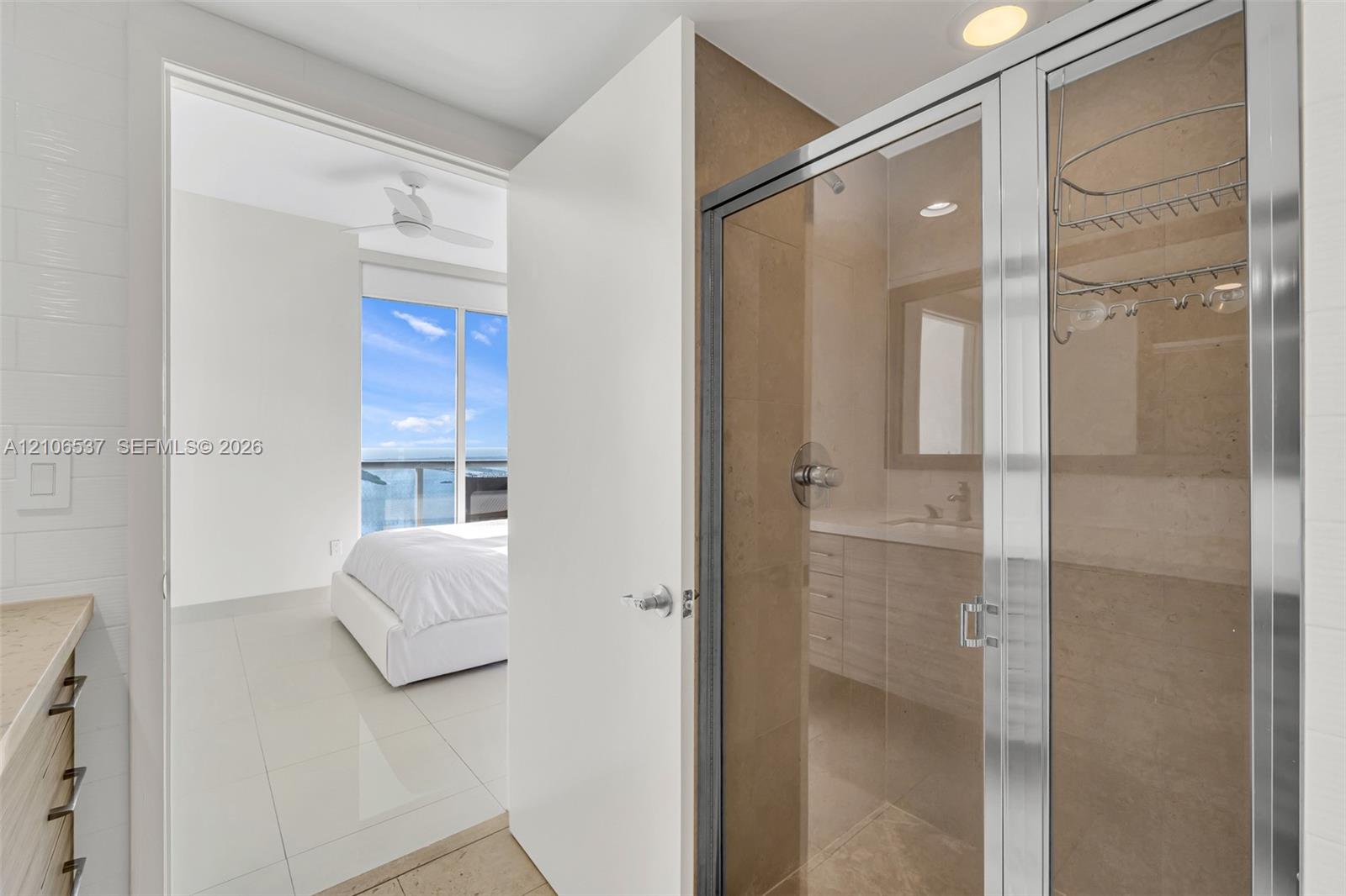 Glass-enclosed shower with tiled surround, stone-top vanity, tile flooring, and recessed lighting