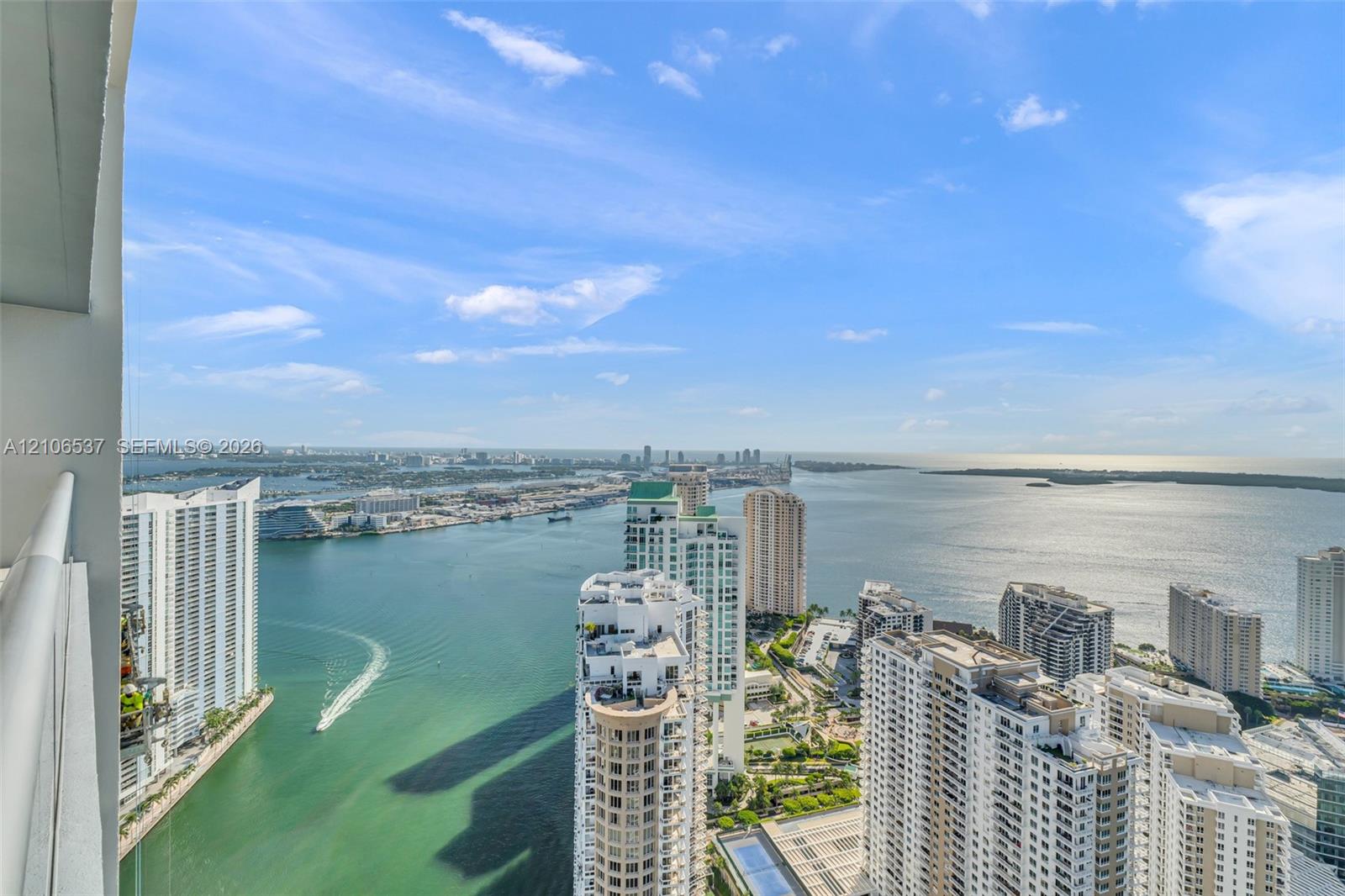 High-rise balcony featuring a metal railing, spanning an expansive, elevated perspective of the surrounding bay, skyline, and coastal waters