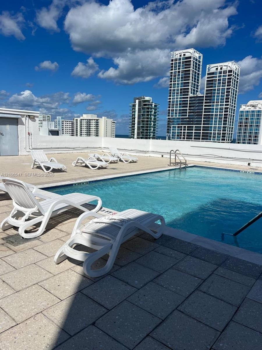 Rooftop swimming pool featuring stone paver decking and integrated stainless steel pool ladder