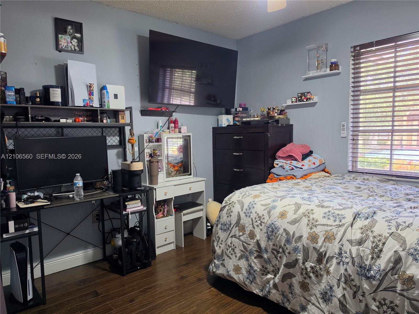 Wood-finish flooring, horizontal window blinds, and two wall-mounted floating shelves