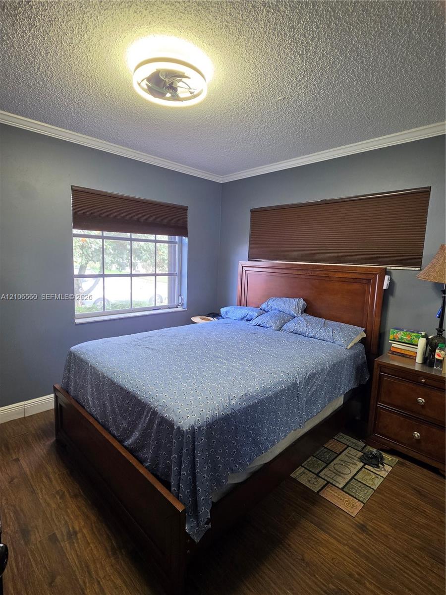 Wood-finish flooring, crown molding, and a multi-pane window with custom cellular shades