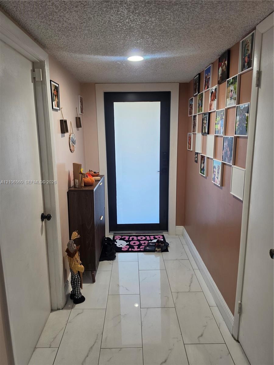 Entryway featuring a black-framed door with a frosted glass panel, recessed ceiling lighting, and light-toned large-format tile flooring Entryway featuring a black-framed door with a frosted glass panel, recessed ceiling lighting, and light-toned large-format tile flooring