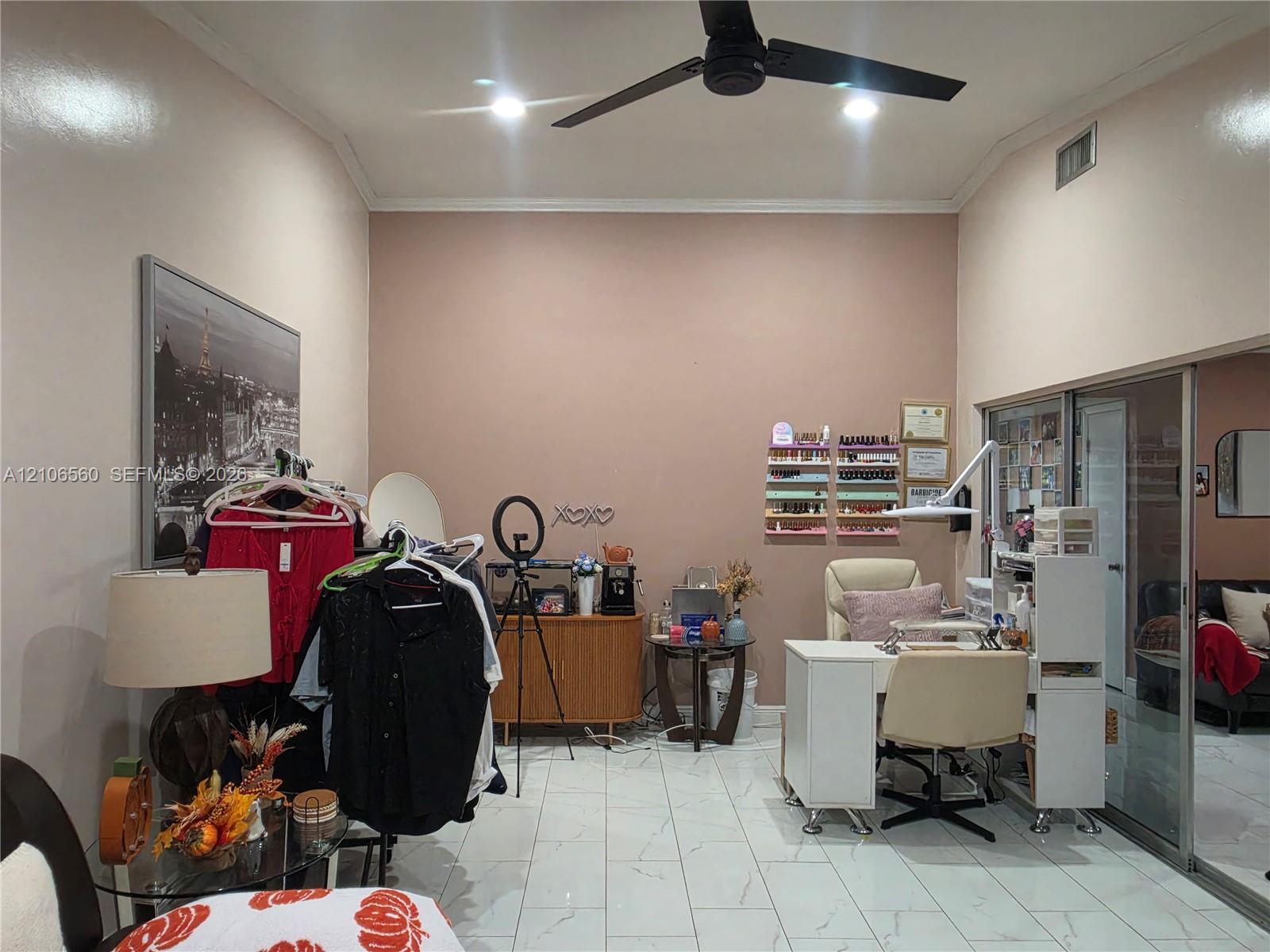 Room featuring high vaulted ceilings, large-format tile flooring, a matte black ceiling fan, and sliding glass entry doors Room featuring high vaulted ceilings, large-format tile flooring, a matte black ceiling fan, and sliding glass entry doors