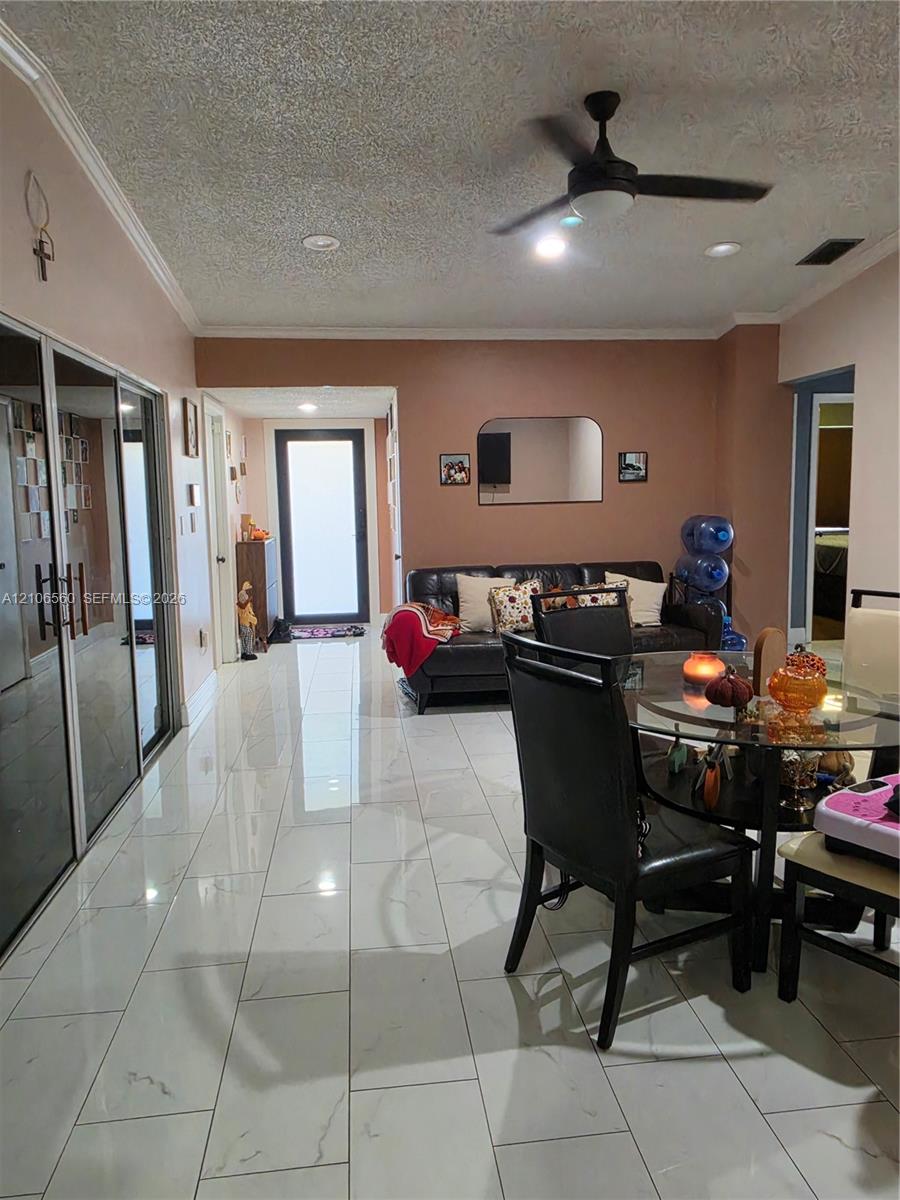 Large-format white tile flooring, ceiling fan with integrated lighting, recessed lighting, and expansive mirrored closet doors