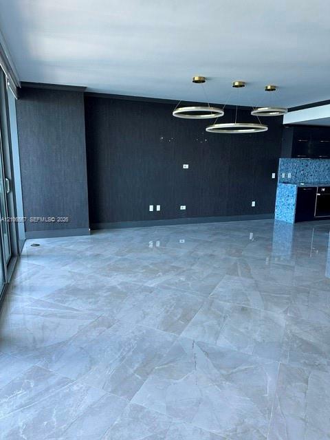 Polished large-format tile flooring, textured charcoal accent wall, and three-ring contemporary pendant lighting