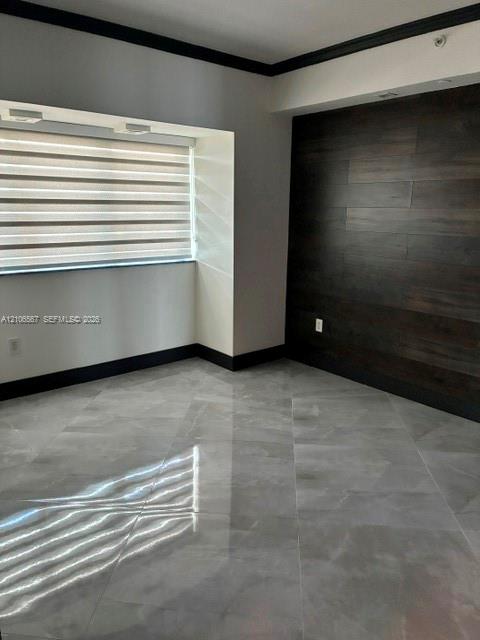 Polished large-format tile flooring, dark wood-finish wall paneling, deep-tone crown molding, and dual-layered window shades