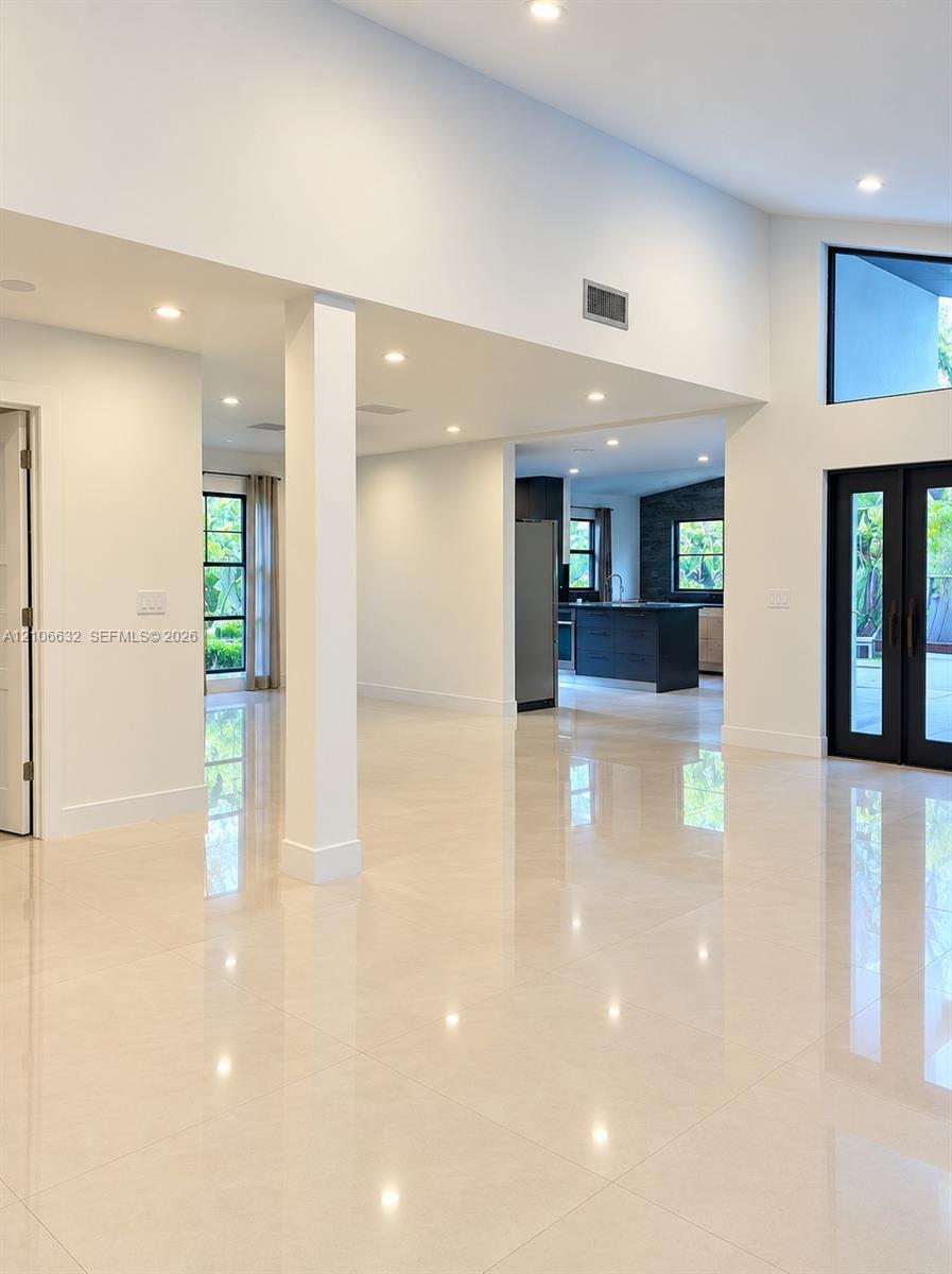 Open interior featuring large-format tile flooring, vaulted ceilings, recessed lighting, access to the garden & terrace.