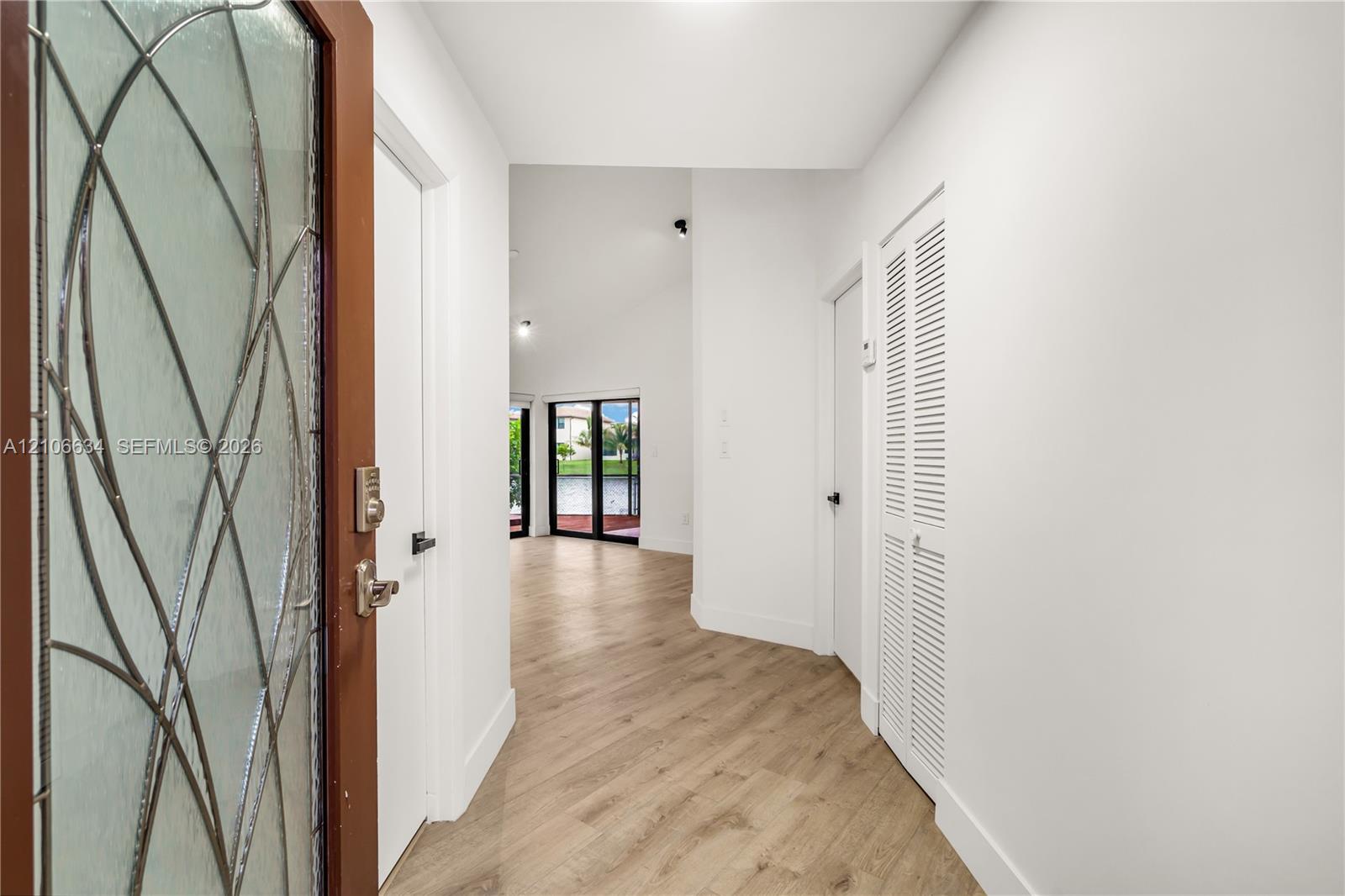 Entryway featuring a front door with decorative glass - white door to the right is the primary bedroom entrance