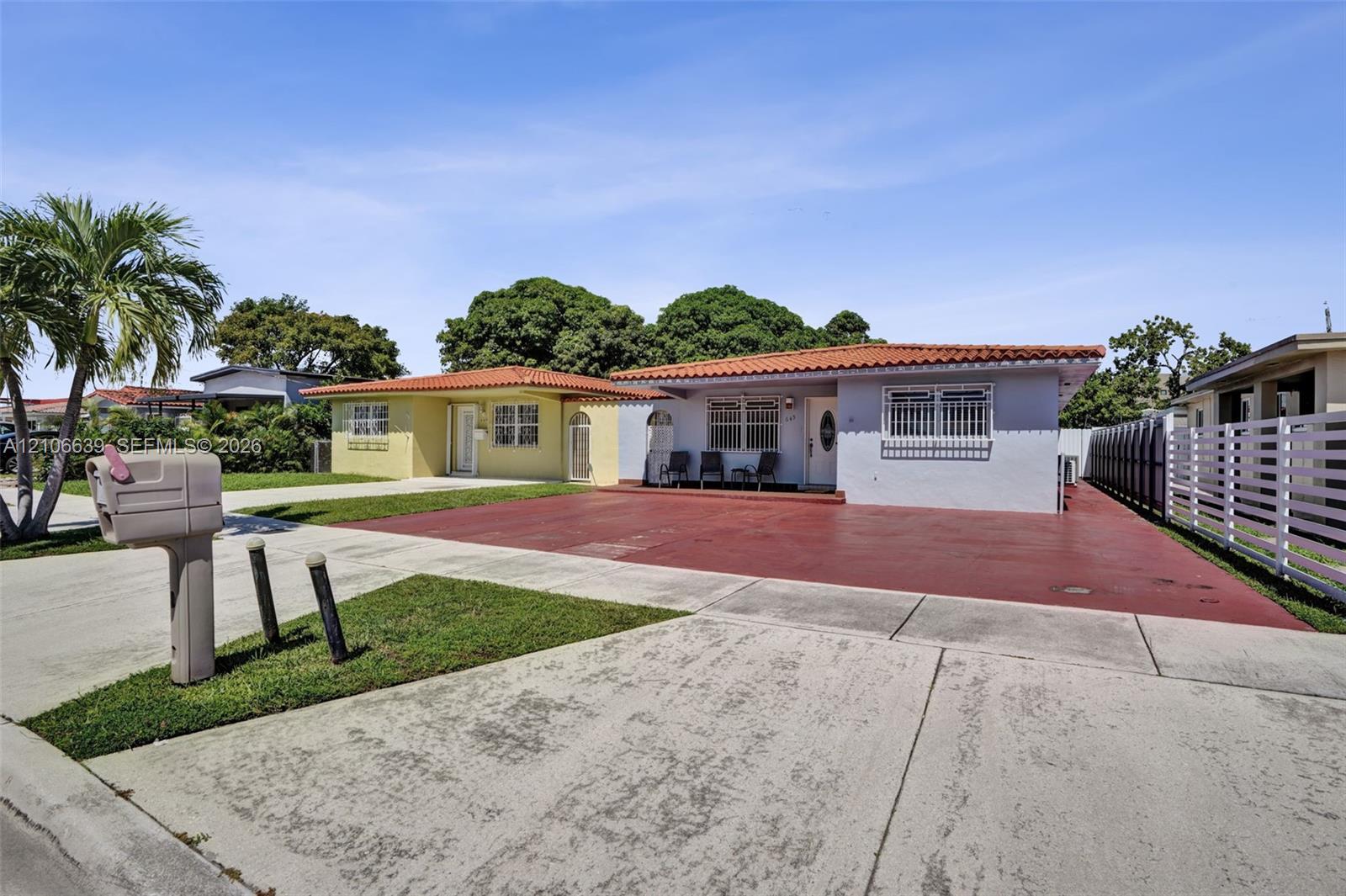 Single-story residence featuring a Mediterranean-style clay tile roof, concrete driveway, and exterior window security bars