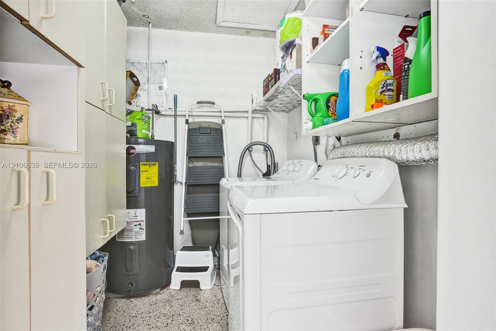 Utility room featuring built-in cabinetry, overhead shelving, and dedicated laundry hookups