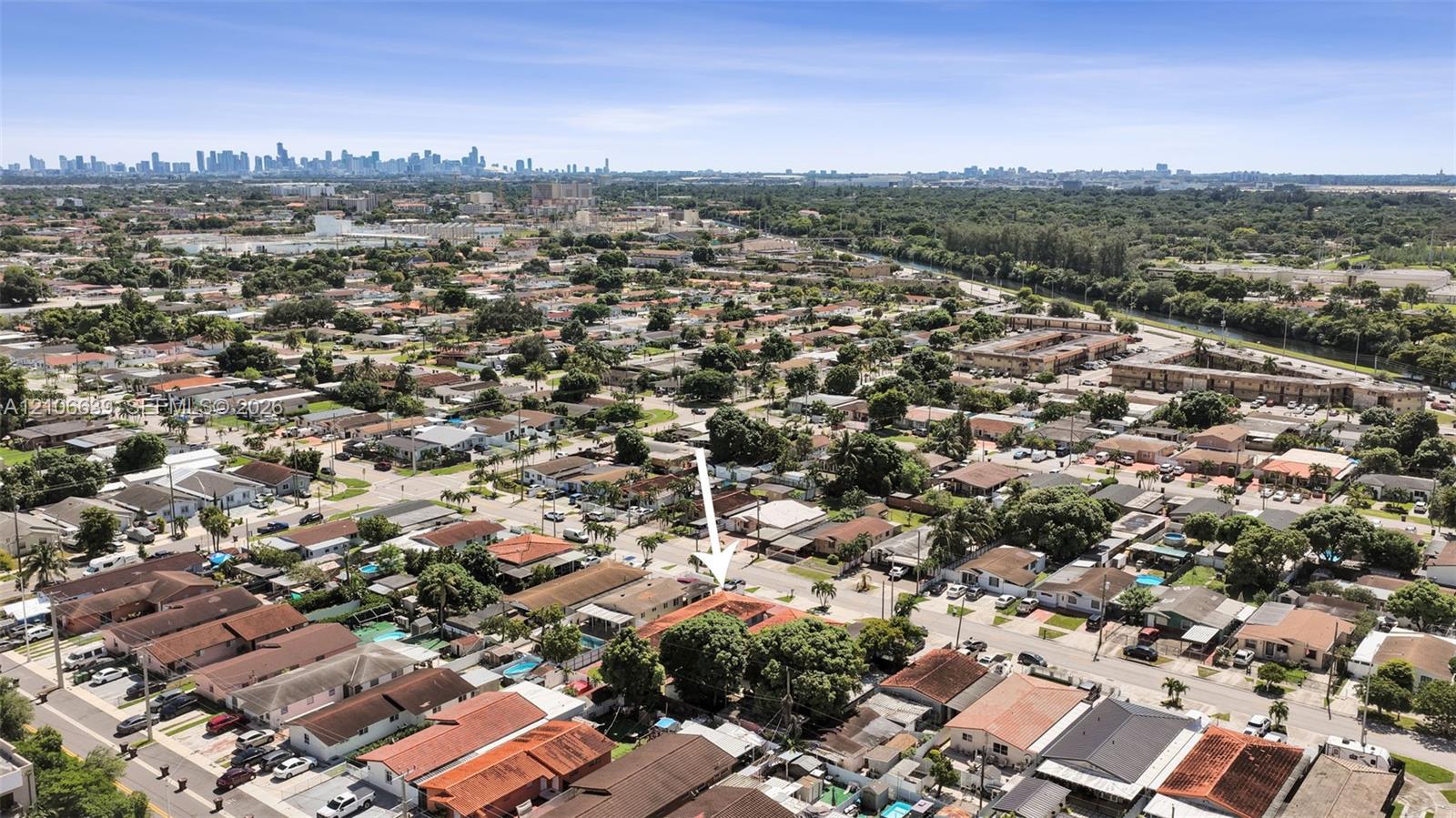 Aerial perspective of residential property featuring a clay tile roof, mature canopy trees, and established landscaping