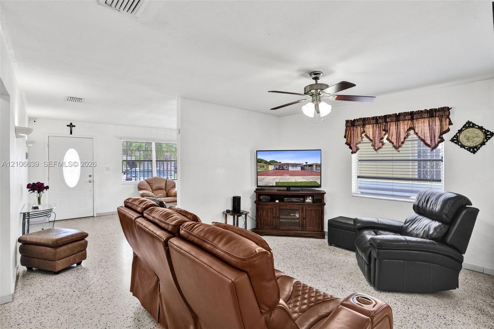Living area featuring speckled stone-finish flooring, a ceiling fan with integrated lighting, and horizontal sliding windows