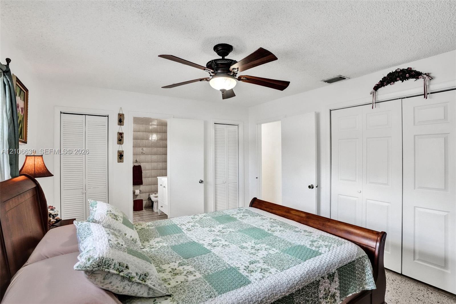Room interior featuring a ceiling fan with integrated lighting, dual bi-fold closet doors, and smooth textured ceilings