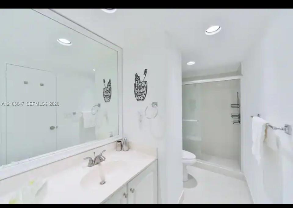 Full-width mirror, vanity with integrated sink, chrome-finished hardware, and walk-in shower enclosure with sliding glass doors