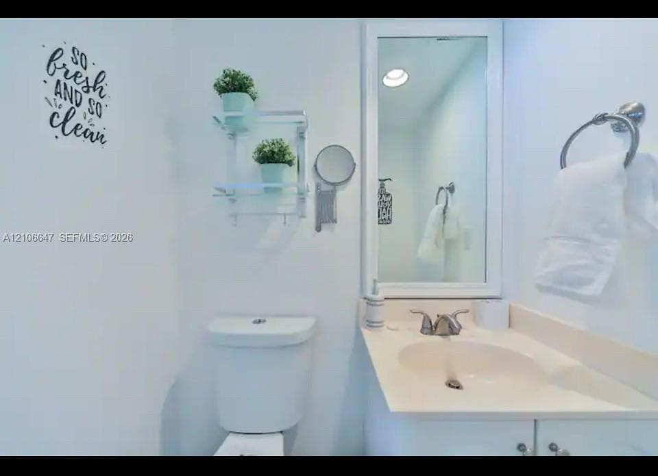 Bathroom featuring a vanity with an integrated sink and countertop, framed wall mirror, polished chrome dual-handle faucet, and polished chrome towel ring