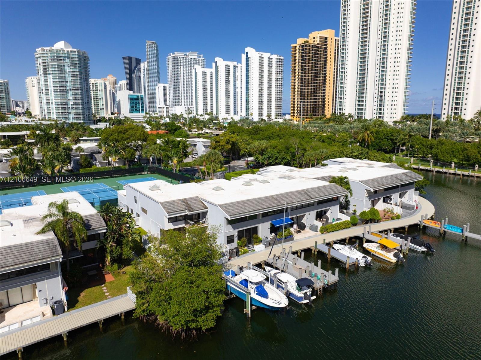Waterfront property featuring a private deep-water dock, integrated boat slips, paved pathways, and tennis courts