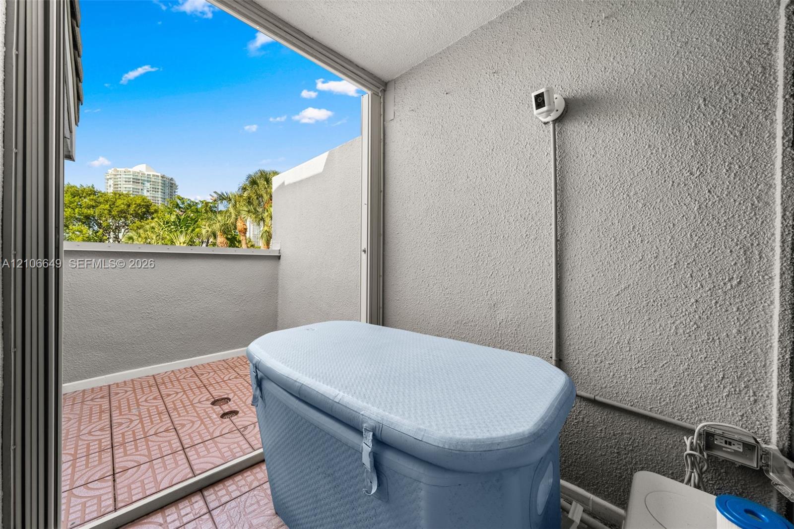 Private balcony featuring tiled flooring, a textured masonry wall, and a low-profile perimeter wall