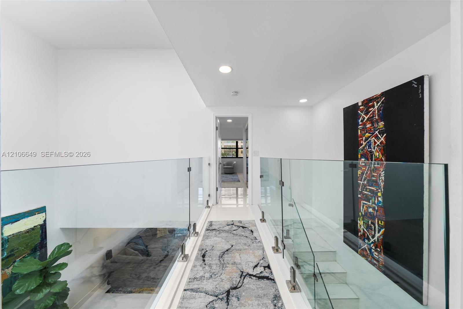 Hallway featuring glass panel railings, metal hardware, stone-finish flooring, and recessed ceiling lighting