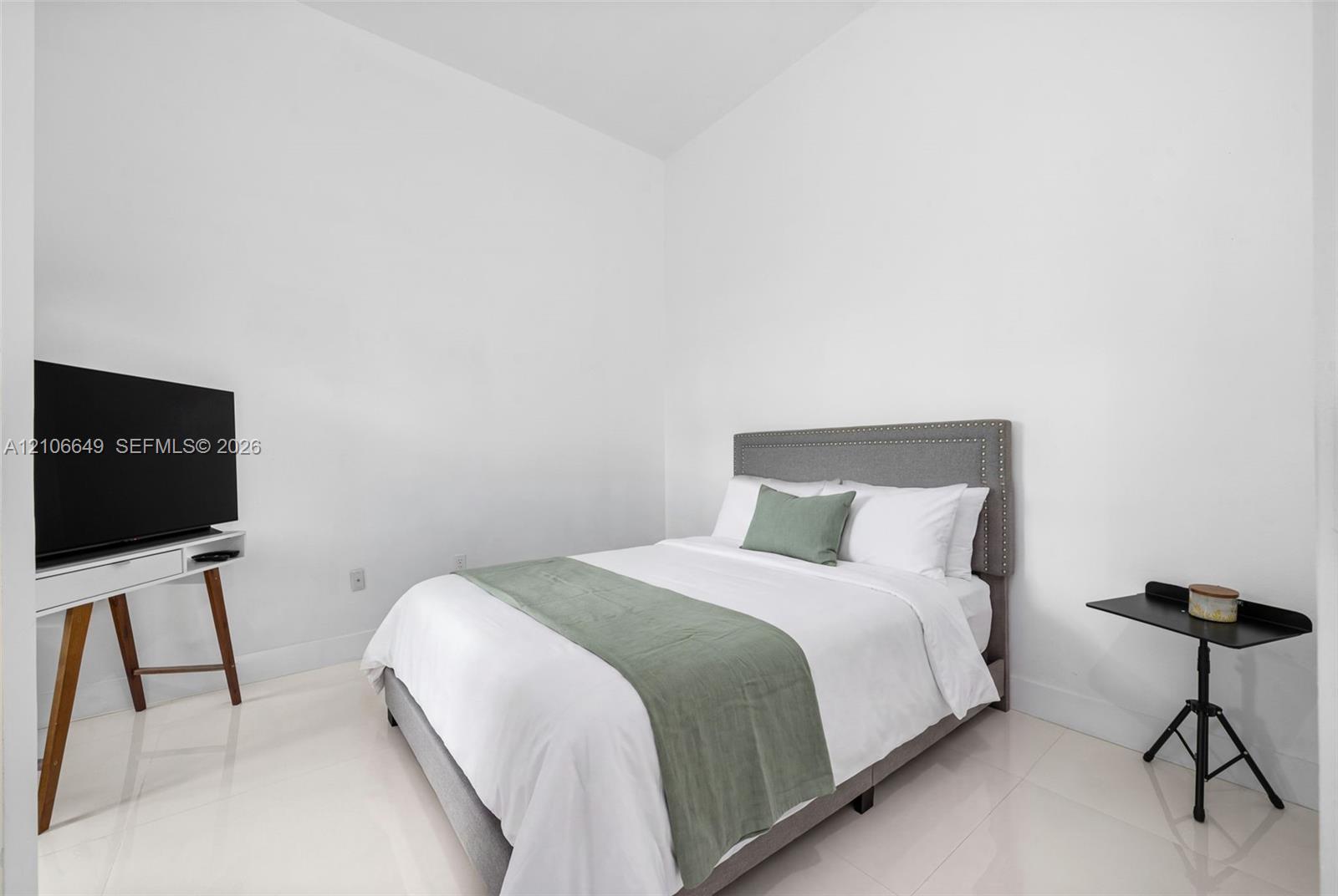 High-ceilinged room featuring neutral white walls and polished porcelain flooring