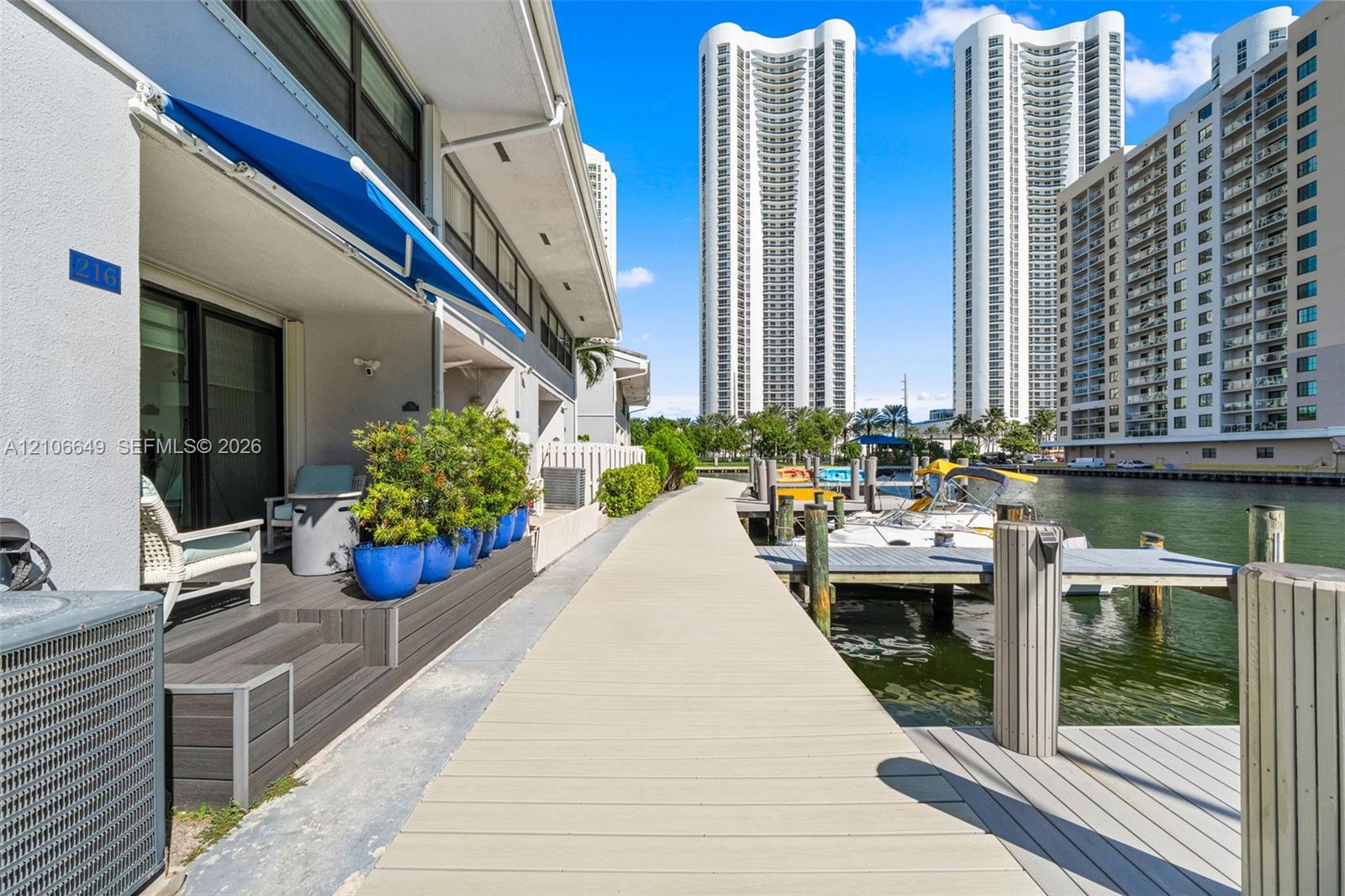 Waterfront terrace featuring composite decking, an retractable fabric awning, and direct access to a private boat dock