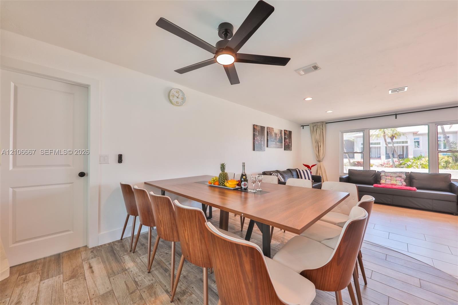 Wood-finish tile flooring, recessed lighting, and a modern black matte ceiling fan with integrated illumination