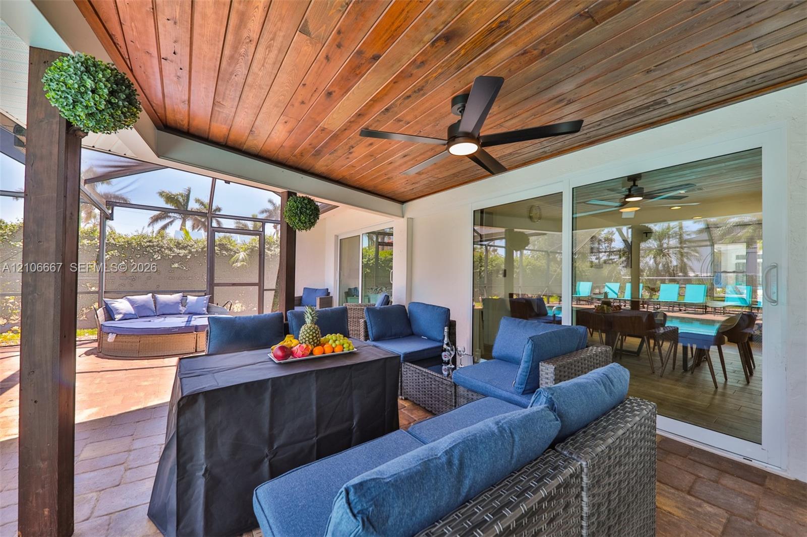 Covered patio featuring a wood-plank ceiling, ceiling fan, paver flooring, and a screened-in enclosure
