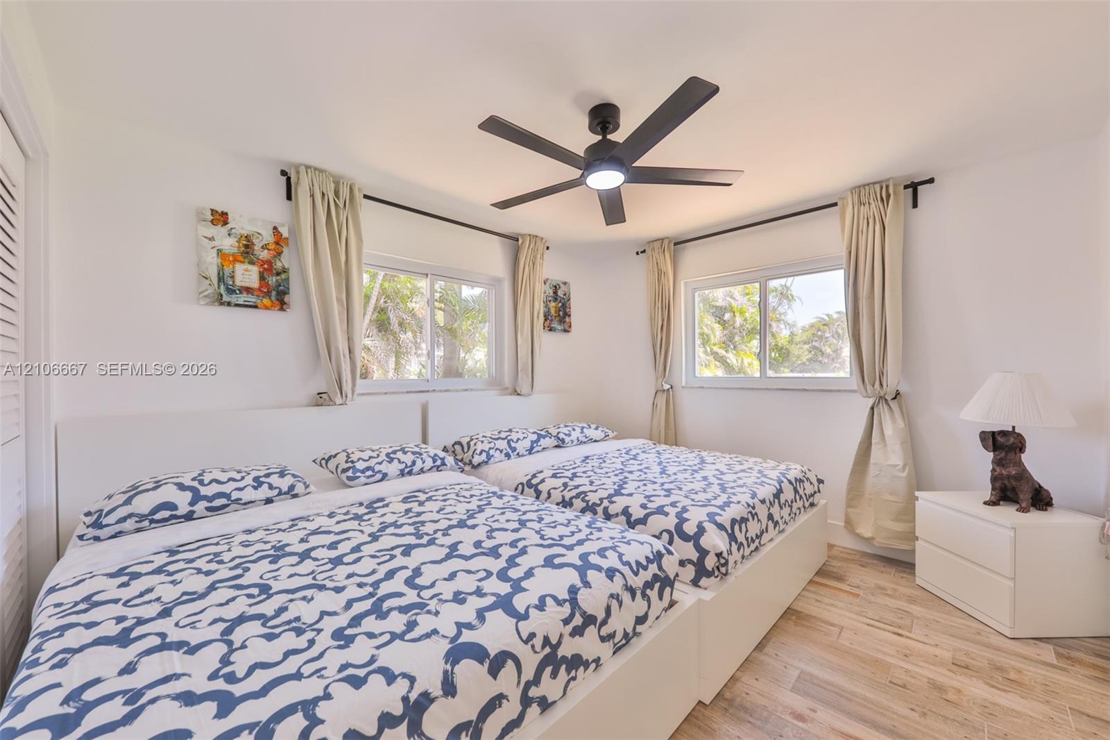 Bedroom featuring wood-finish flooring, dual windows, and a ceiling fan with integrated lighting