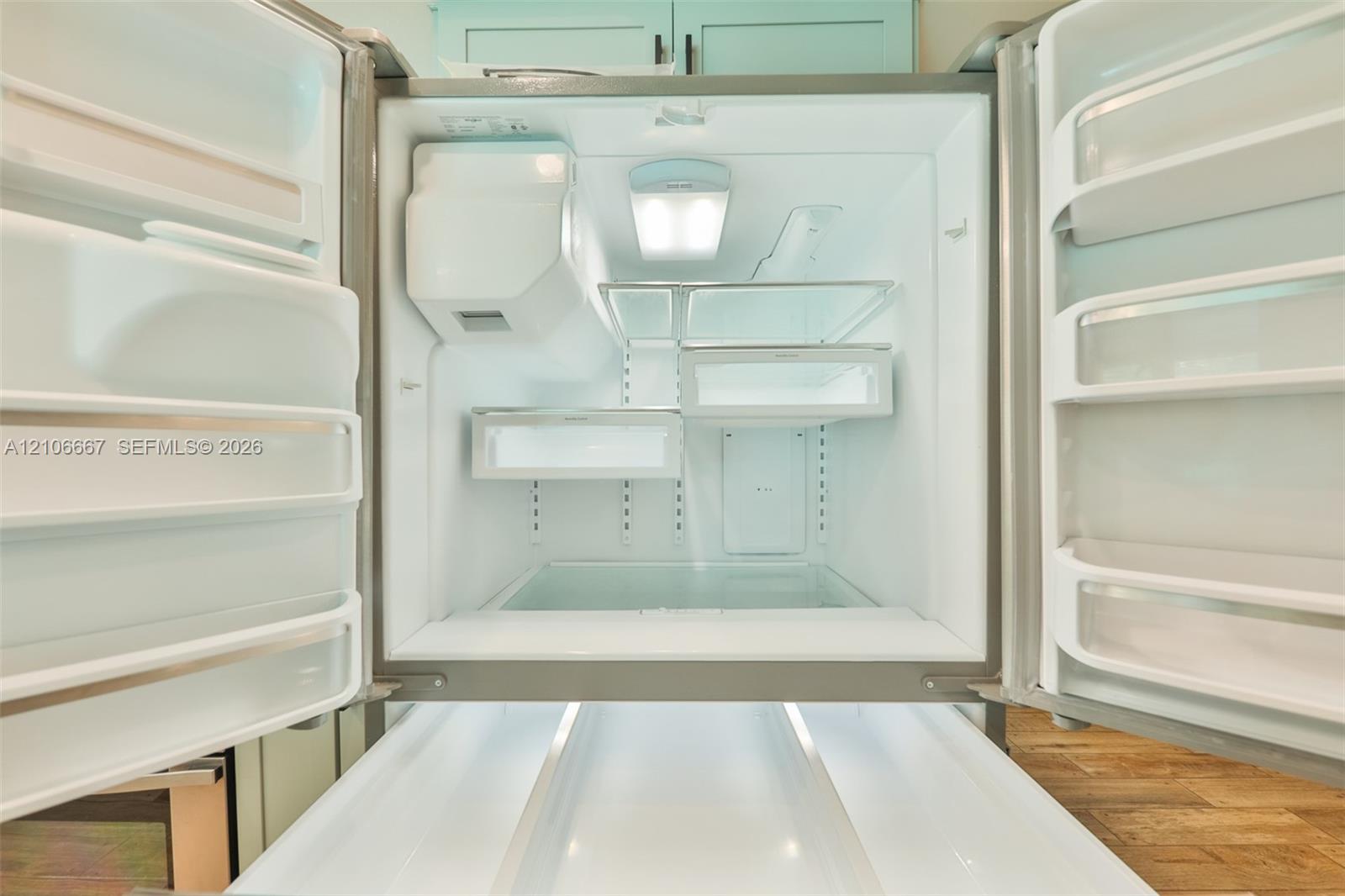 French-door refrigerator featuring adjustable shelving, integrated interior LED lighting, multiple door-mounted storage bins, and a sliding pull-out freezer drawer