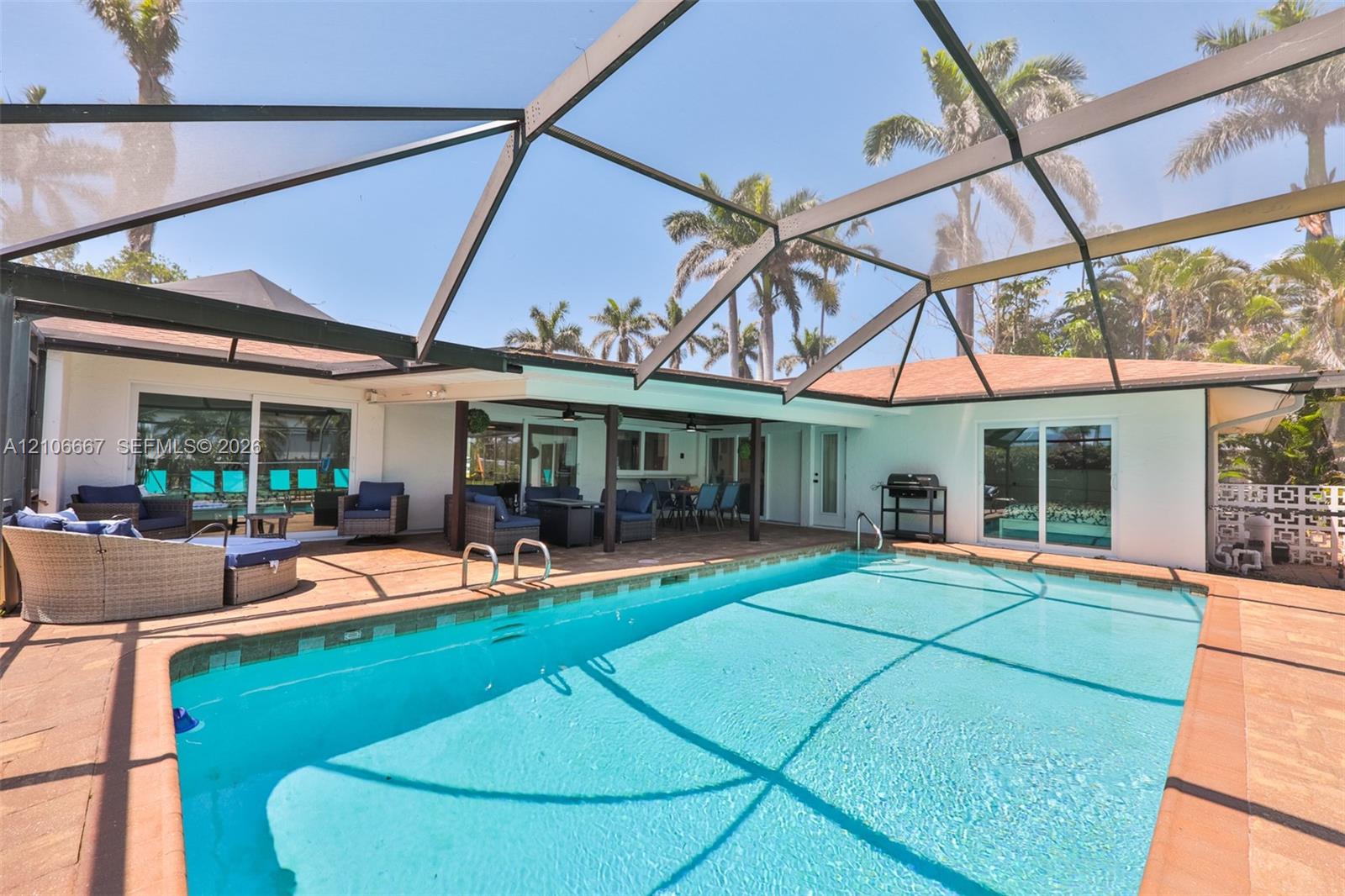 Screened-in pool area featuring a paver deck, covered lanai, and exterior sliding glass doors