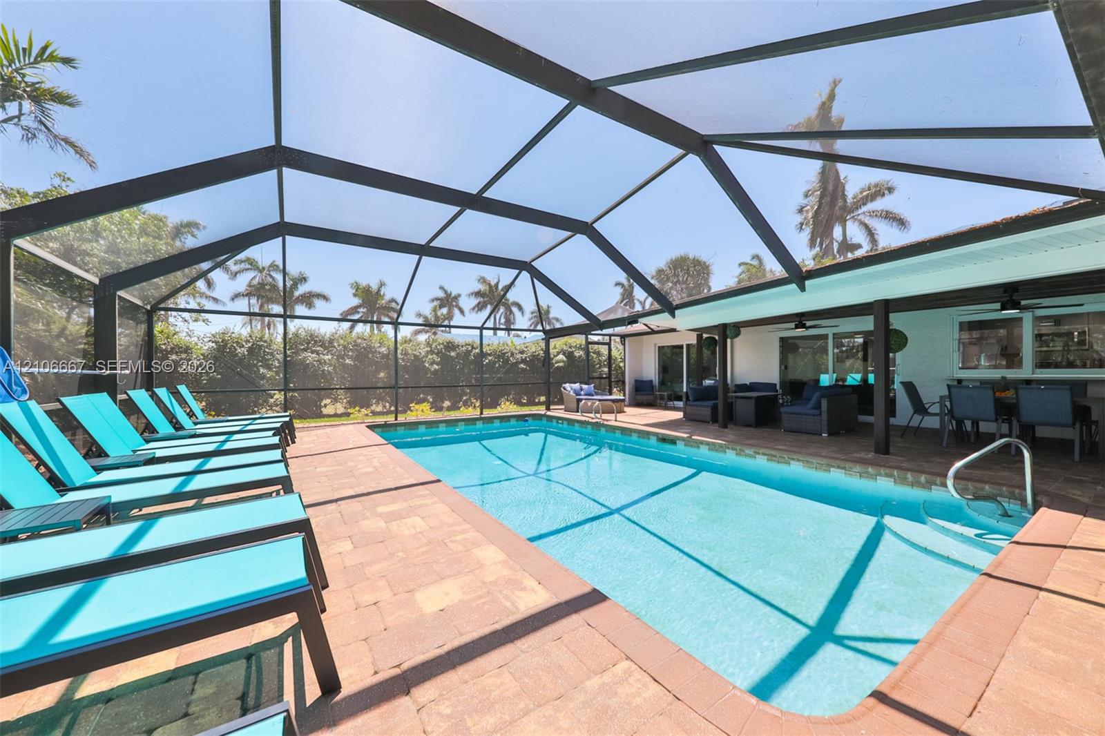 Screen-enclosed swimming pool featuring a paver deck and built-in steps