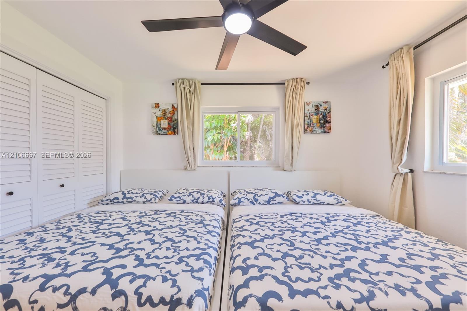 Room featuring louvered-door closet cabinetry, a central ceiling fan with integrated lighting, and multiple windows