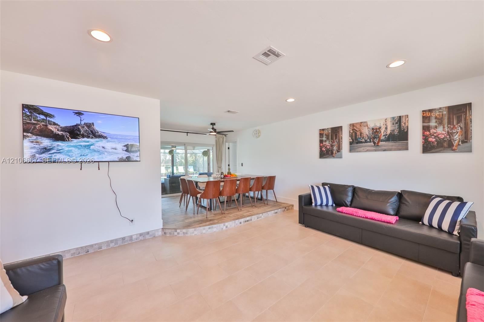Open-concept interior featuring light-toned tile flooring, recessed ceiling lighting, and a multi-level floor plan with a raised dining platform Open-concept interior featuring light-toned tile flooring, recessed ceiling lighting, and a multi-level floor plan with a raised dining platform