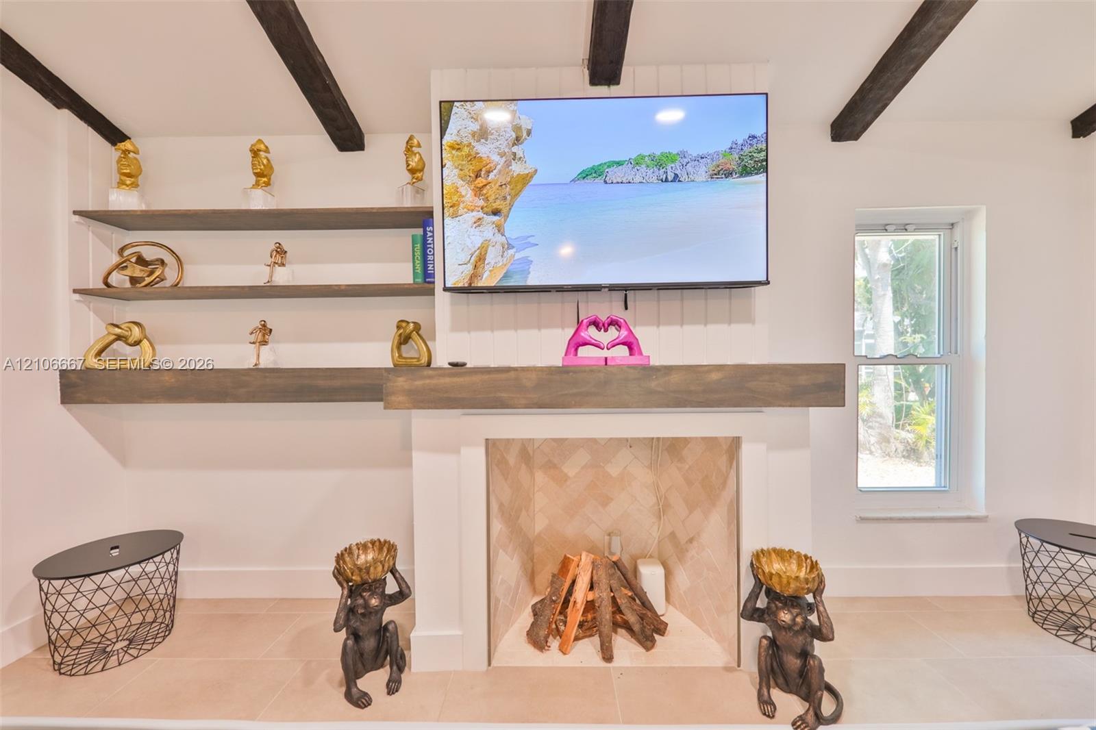Fireplace featuring a herringbone-patterned tile surround, custom wood mantel, built-in shelving, and exposed dark-stained ceiling beams