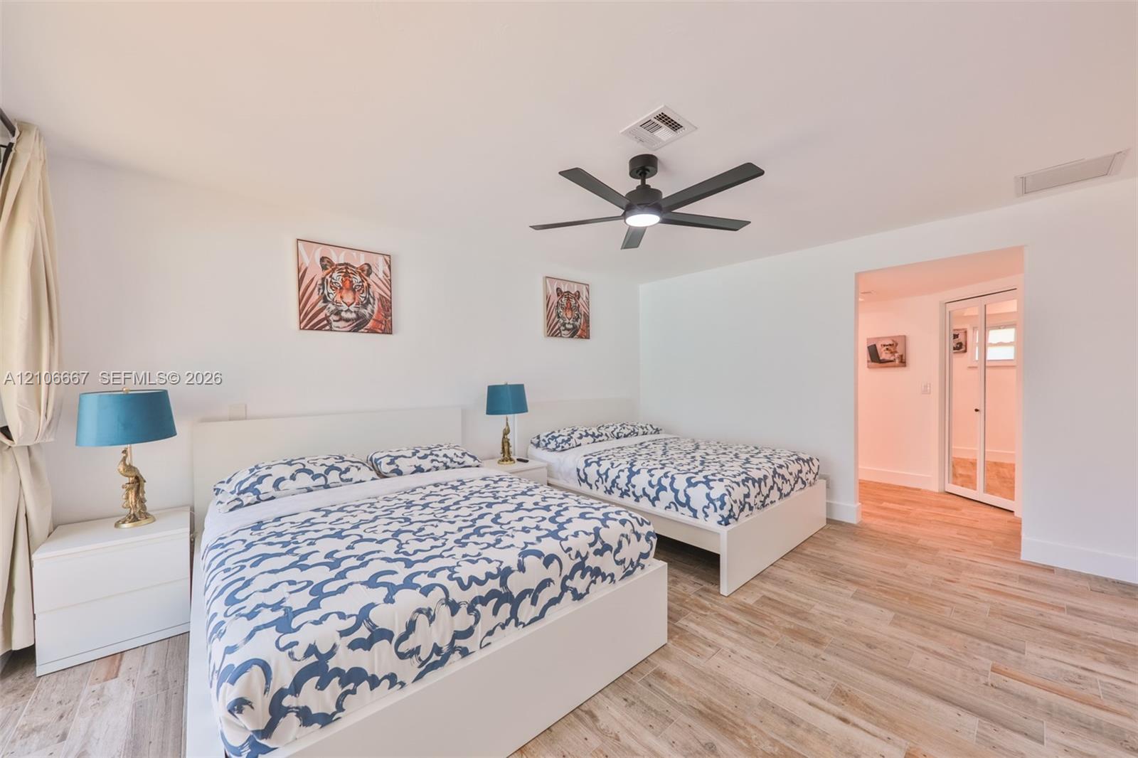 Wood-finish flooring, multi-blade ceiling fan with integrated lighting, and white bi-fold closet doors