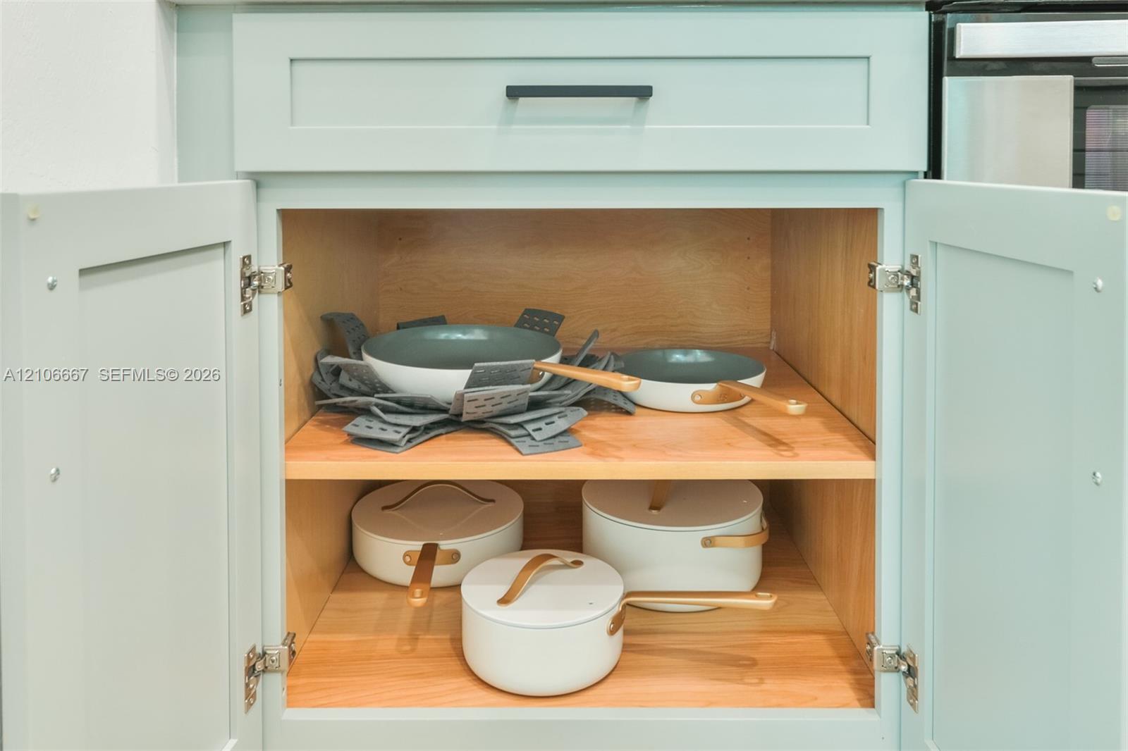 Shaker-style cabinetry with light blue finish, matte black hardware, and natural wood interior shelving