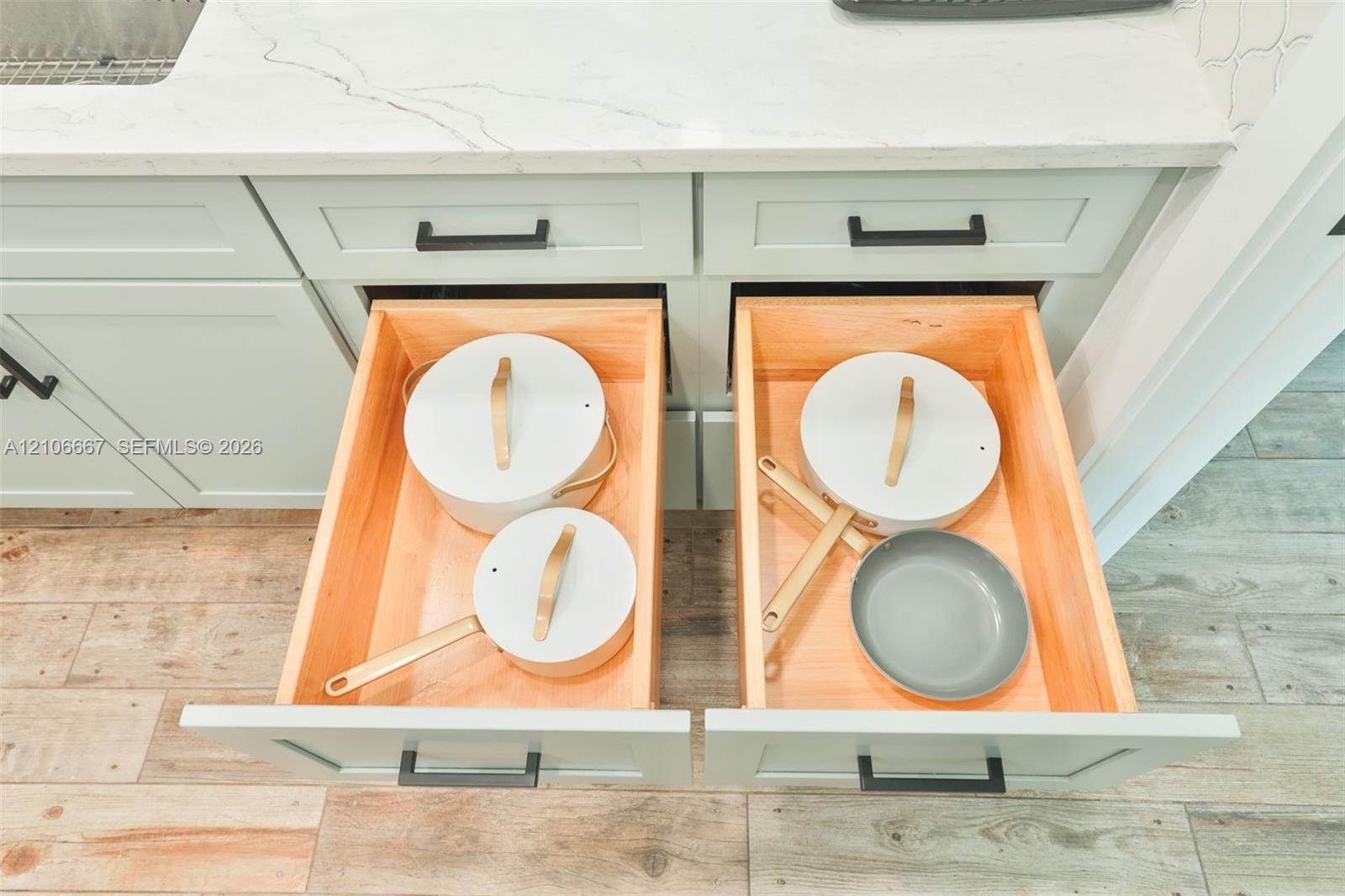 Custom cabinetry with soft-close drawers, stone-finish countertops, matte black hardware, and wood-finish tile flooring