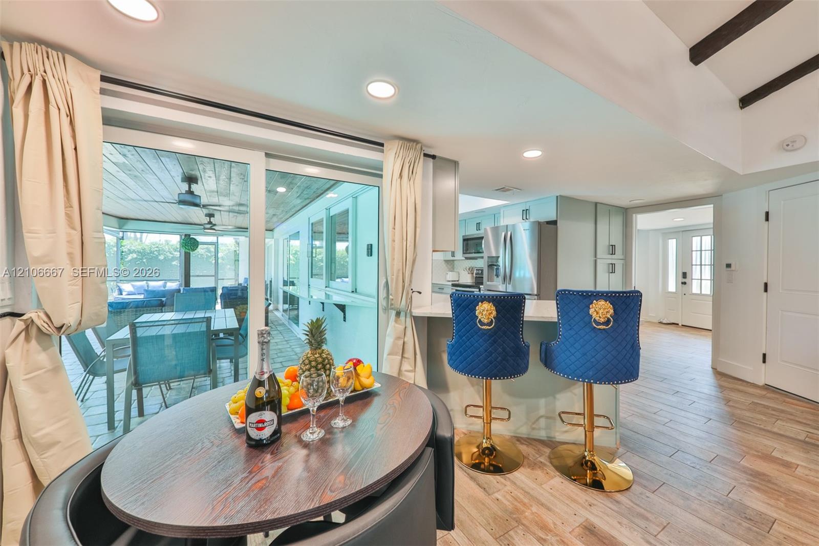 Kitchen featuring wood-finish tile flooring, recessed lighting, white cabinetry, and a stone-surface peninsula with integrated seating