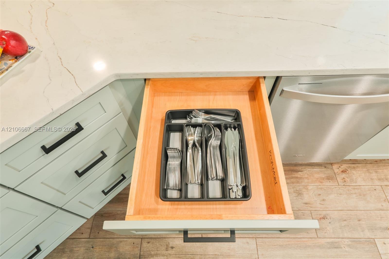 Custom-built wooden drawer with dovetailed joinery, integrated cabinetry with matte black hardware, and stone countertop with veined patterning