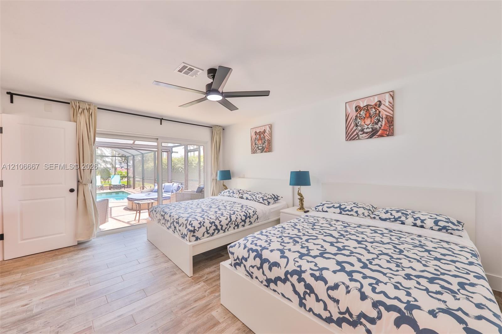 Neutral interior featuring wood-finish flooring, a contemporary multi-blade ceiling fan, and large sliding glass doors providing outdoor access