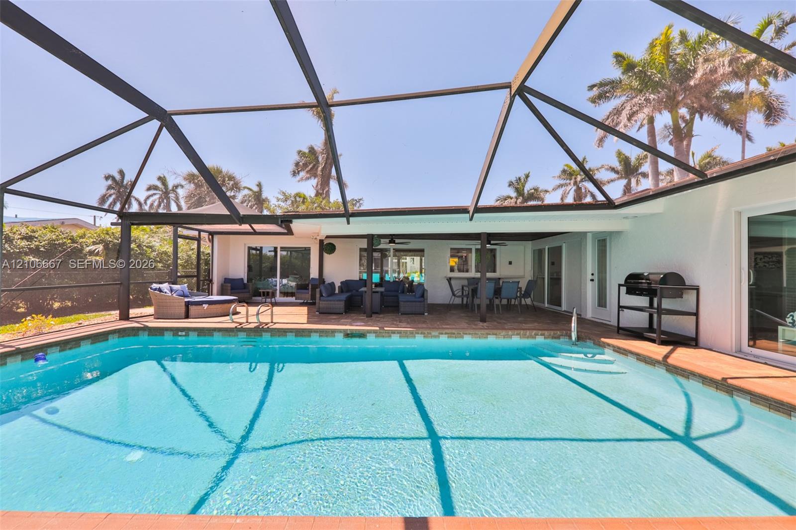 Screened-in pool area featuring a tile-surround swimming pool, covered concrete lanai, and glass sliding door access