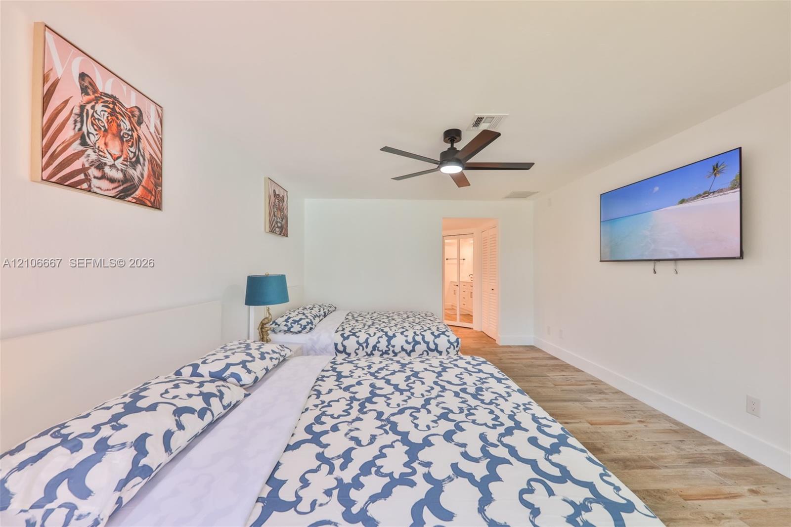 Spacious room featuring wood-finish flooring, a ceiling fan with integrated lighting, and white walls