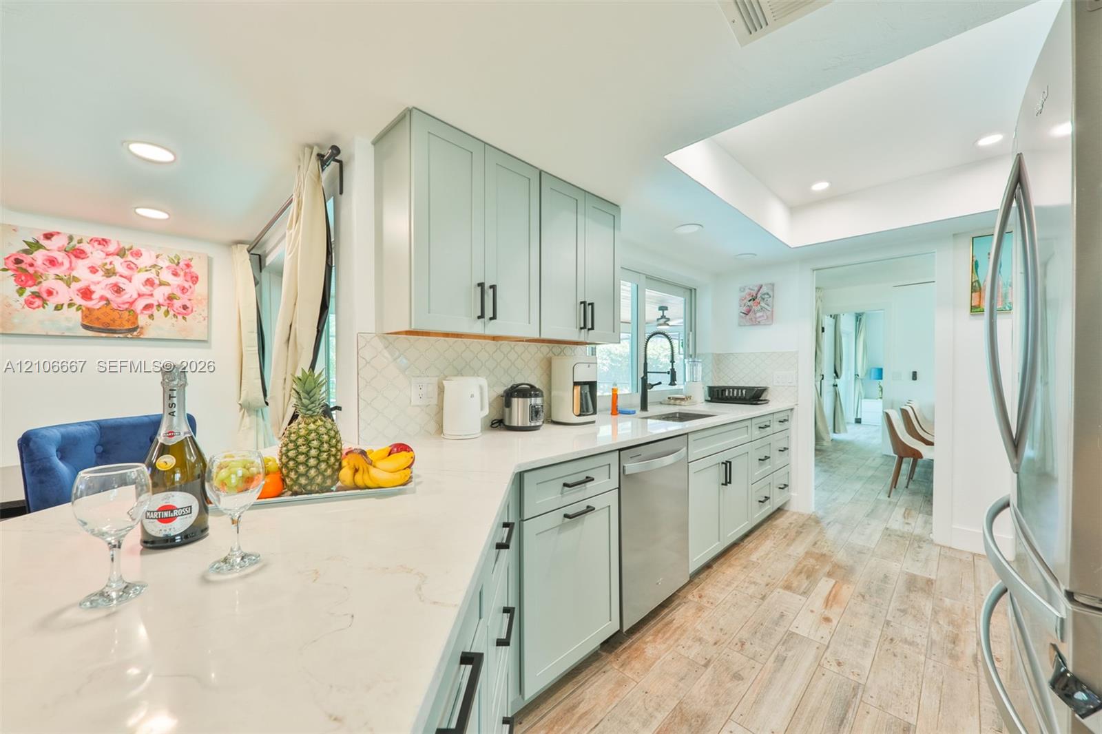 Kitchen featuring custom cabinetry, stone-finish countertops, stainless steel appliances, a recessed tray ceiling, and wood-finish flooring