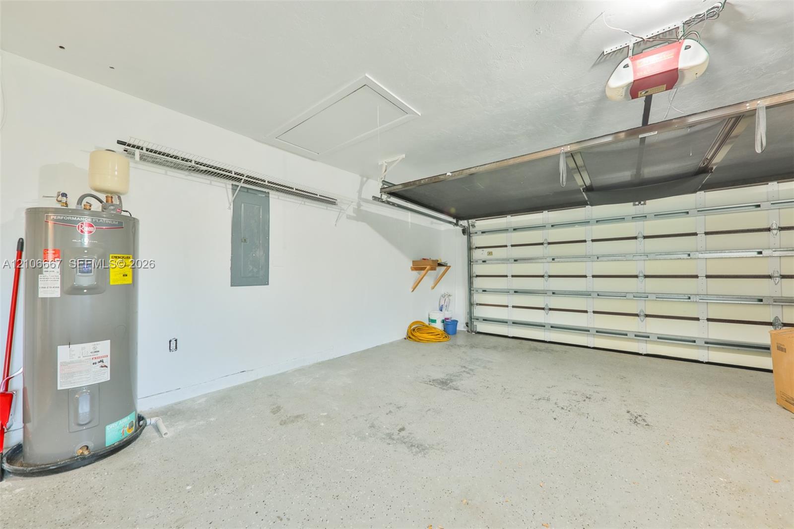 Garage interior featuring a sectional roll-up door, integrated door opener, concrete flooring, and an installed water heater