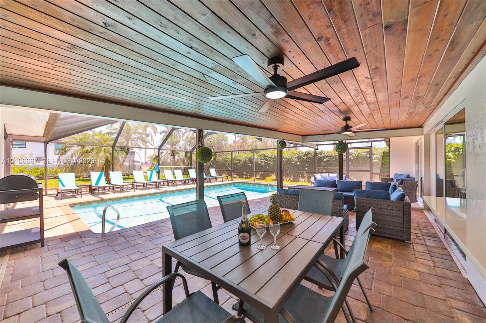 Covered lanai featuring a wood-plank ceiling, recessed lighting, dual ceiling fans, paver flooring, and a screened-in swimming pool