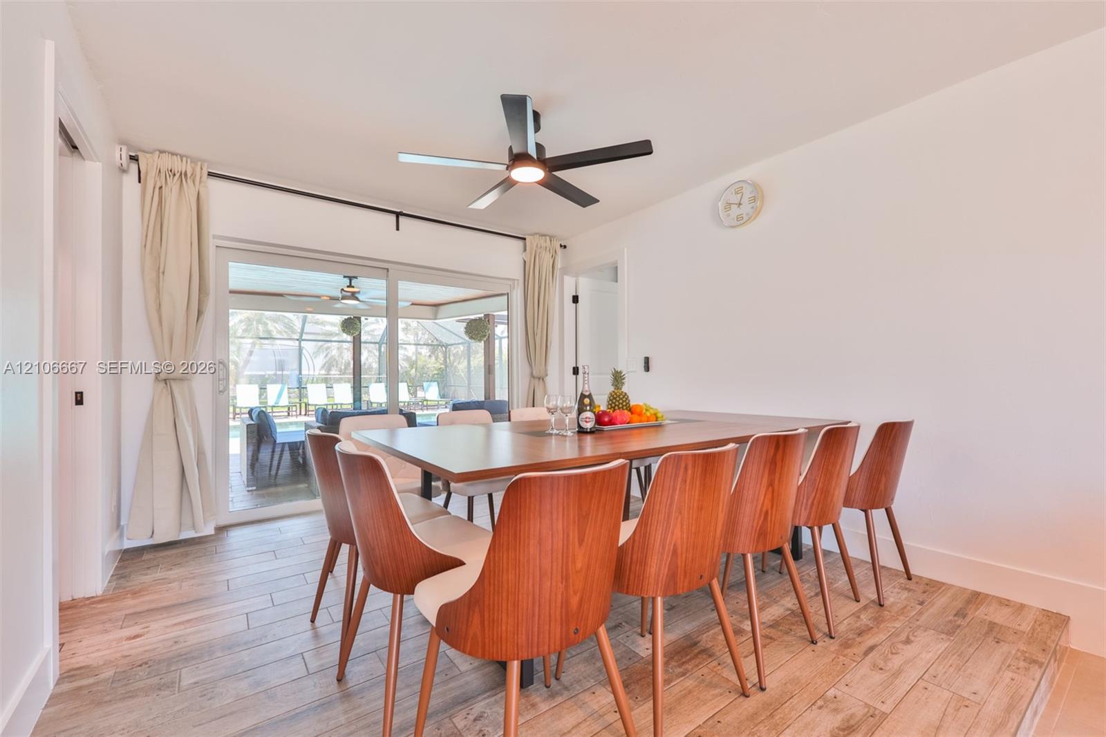 Dining area featuring wood-finish tile flooring, ceiling fan with integrated lighting, and sliding glass doors Dining area featuring wood-finish tile flooring, ceiling fan with integrated lighting, and sliding glass doors